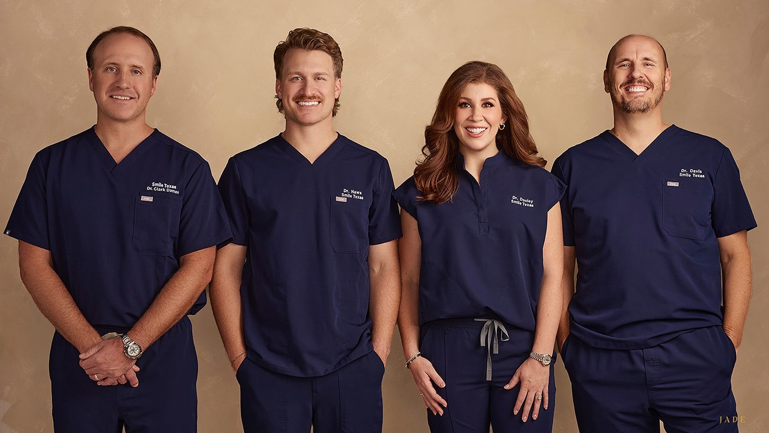 Four dental professionals in navy scrubs.