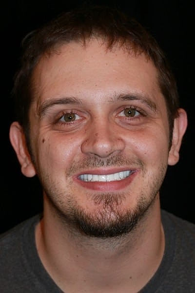 Smiling man against a dark background.