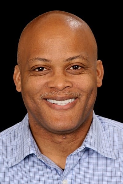 Smiling man in a blue checkered shirt.