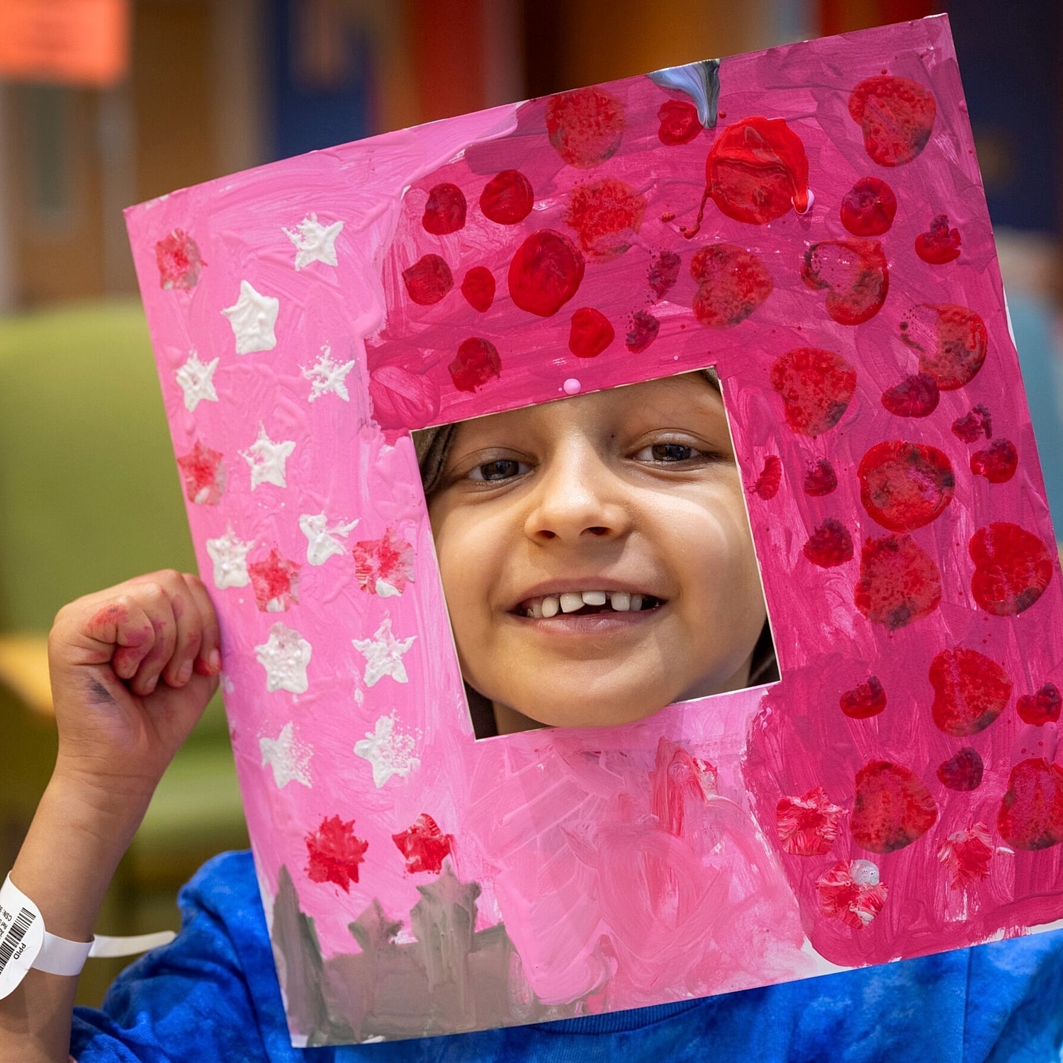 Child holding a colorful handmade picture frame.