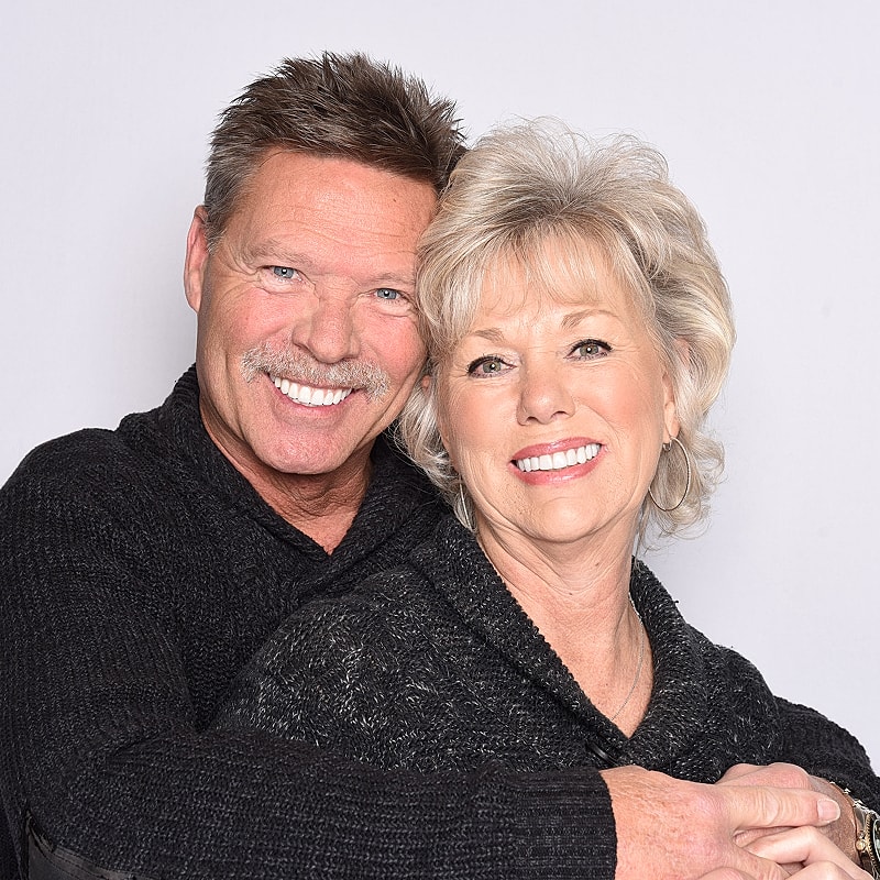 Smiling couple posing together, wearing cozy sweaters.