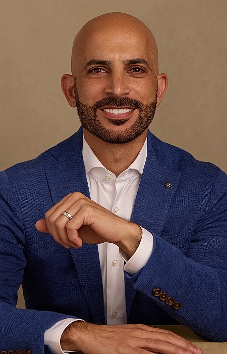Smiling man in blue suit, seated confidently.