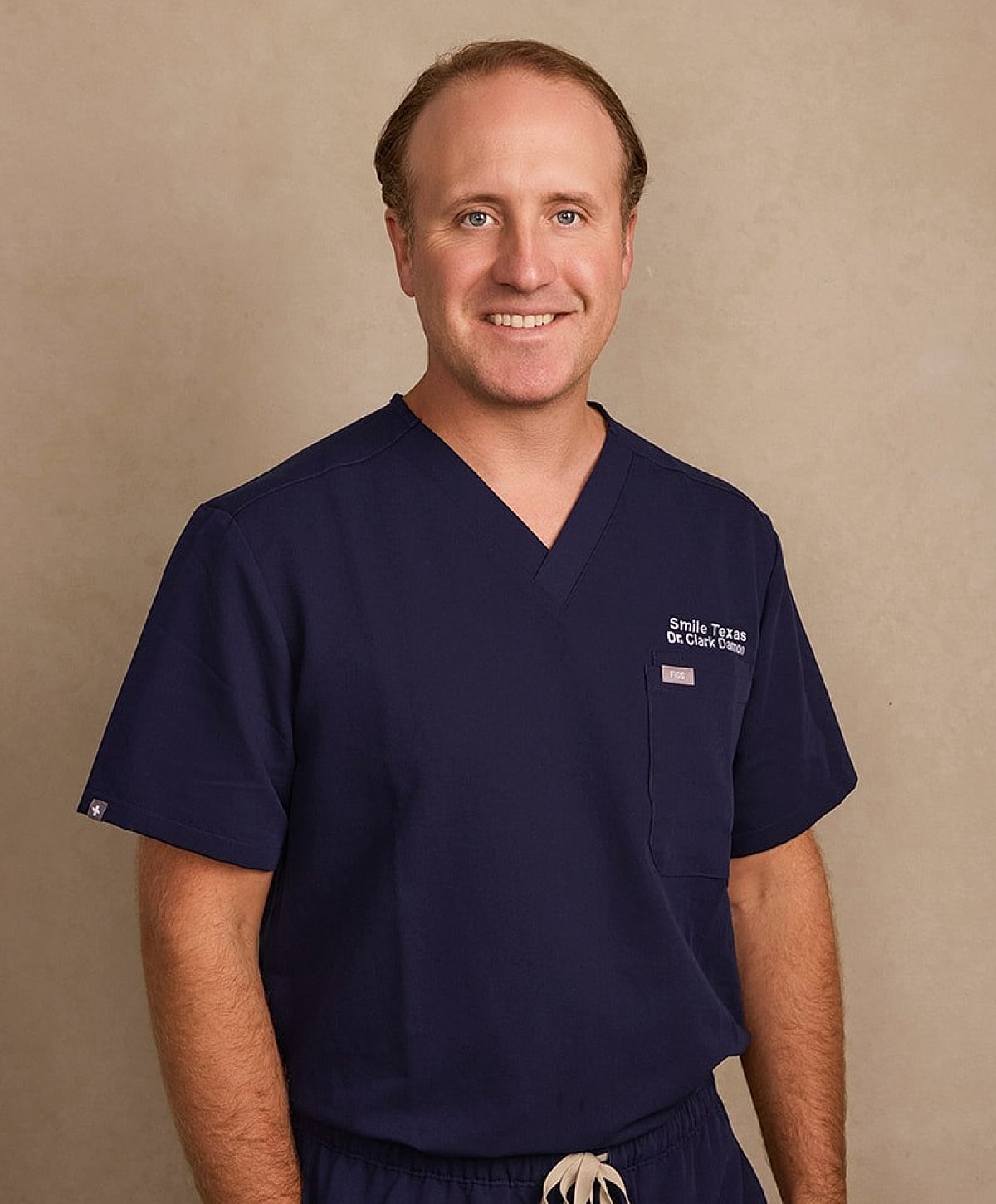 Doctor in scrubs smiling for the camera.
