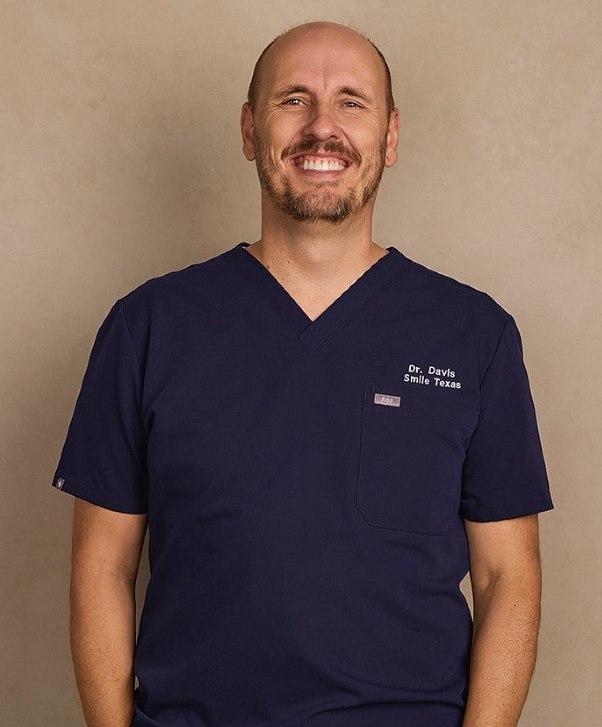 Smiling male dentist in blue scrubs.