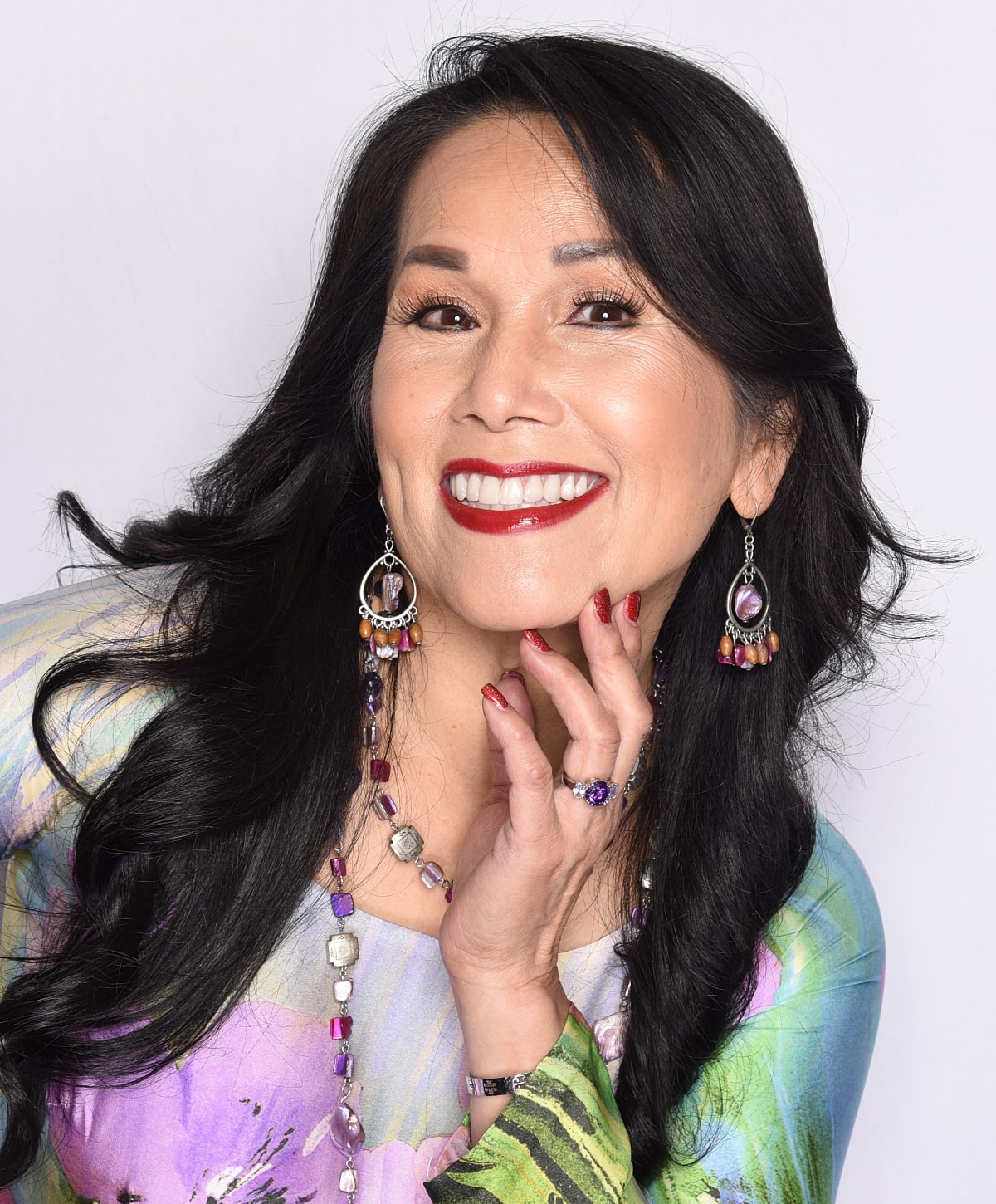 Smiling woman with stylish jewelry and colorful dress.