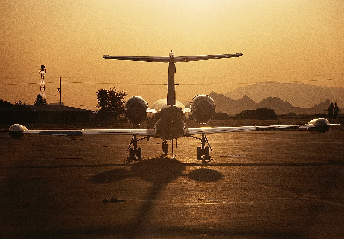 Jet aircraft at sunset on airport runway.