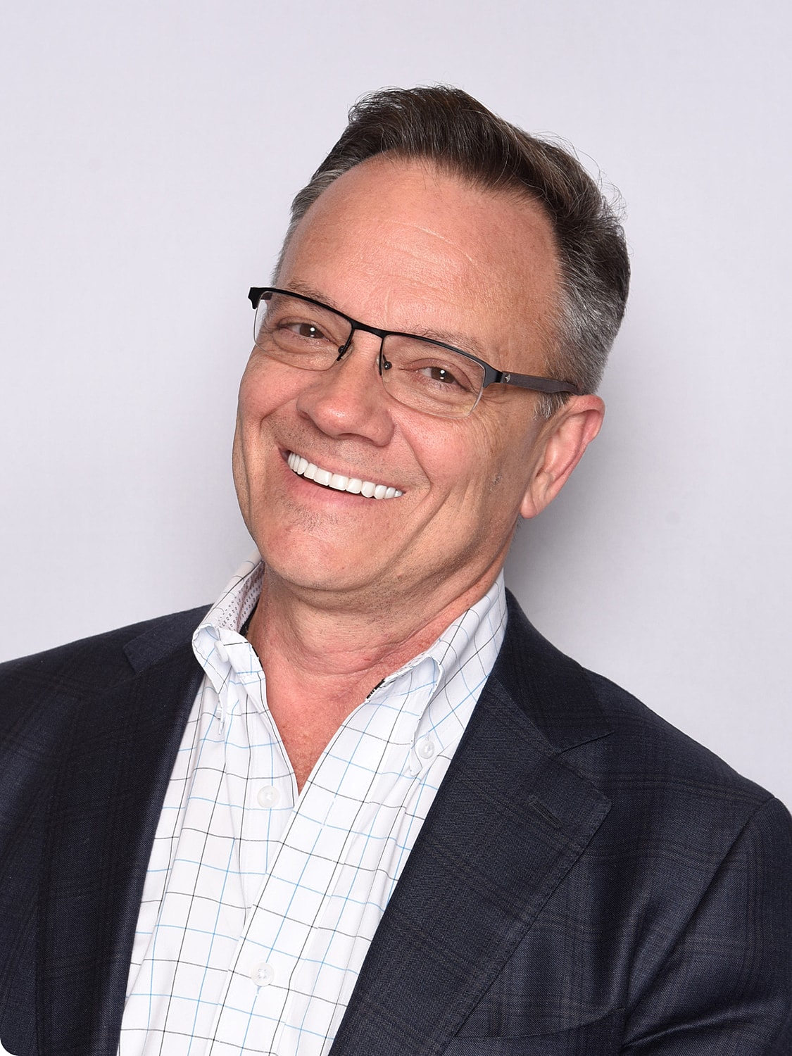 Smiling man in glasses and suit jacket.