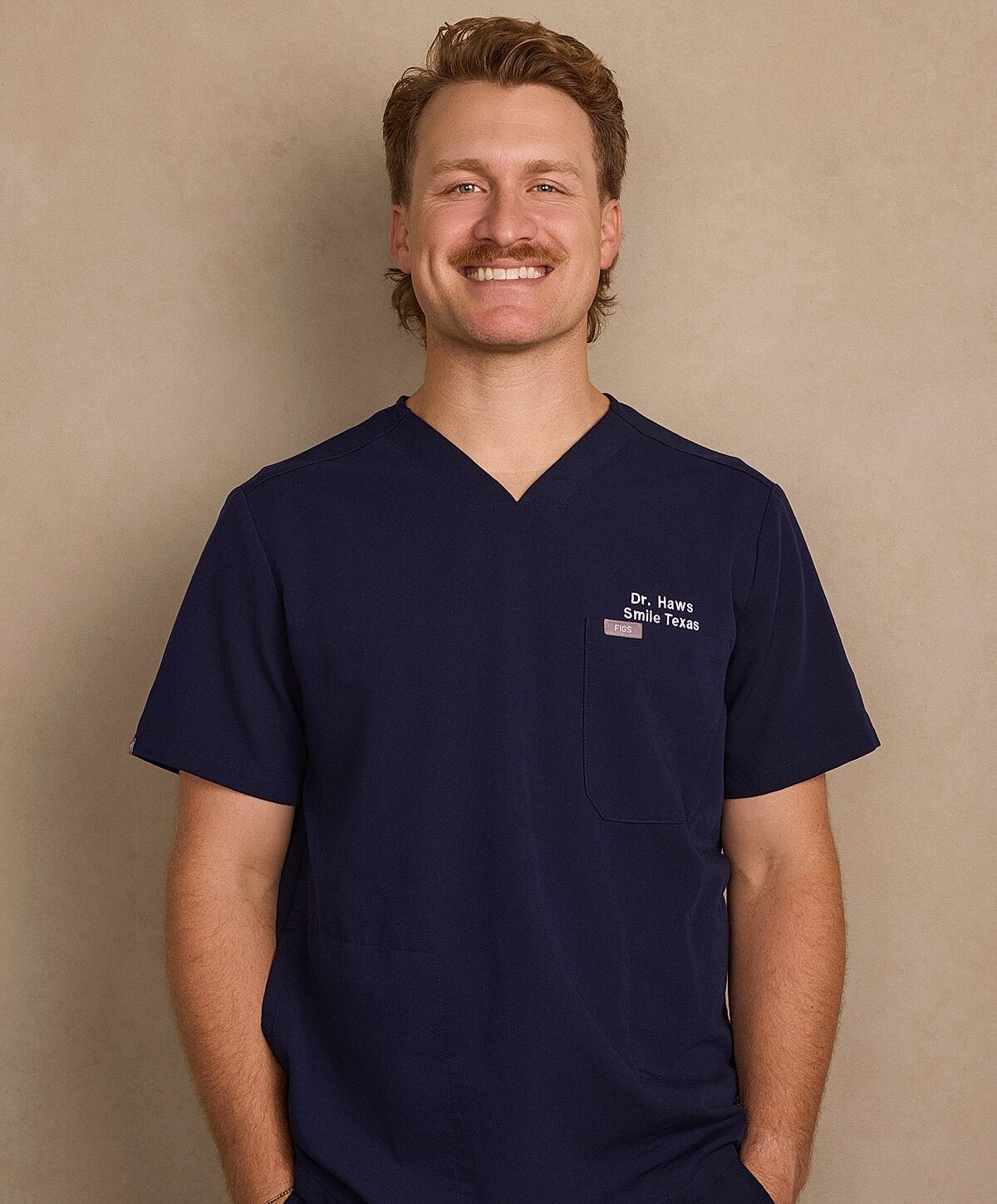 Smiling man in medical scrubs against neutral background.