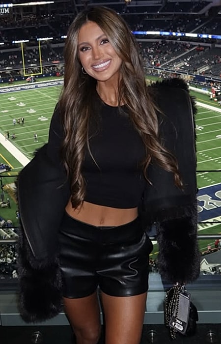 Woman smiling in stylish outfit at stadium.