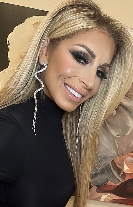 Woman with blonde hair and jewelry, smiling. 