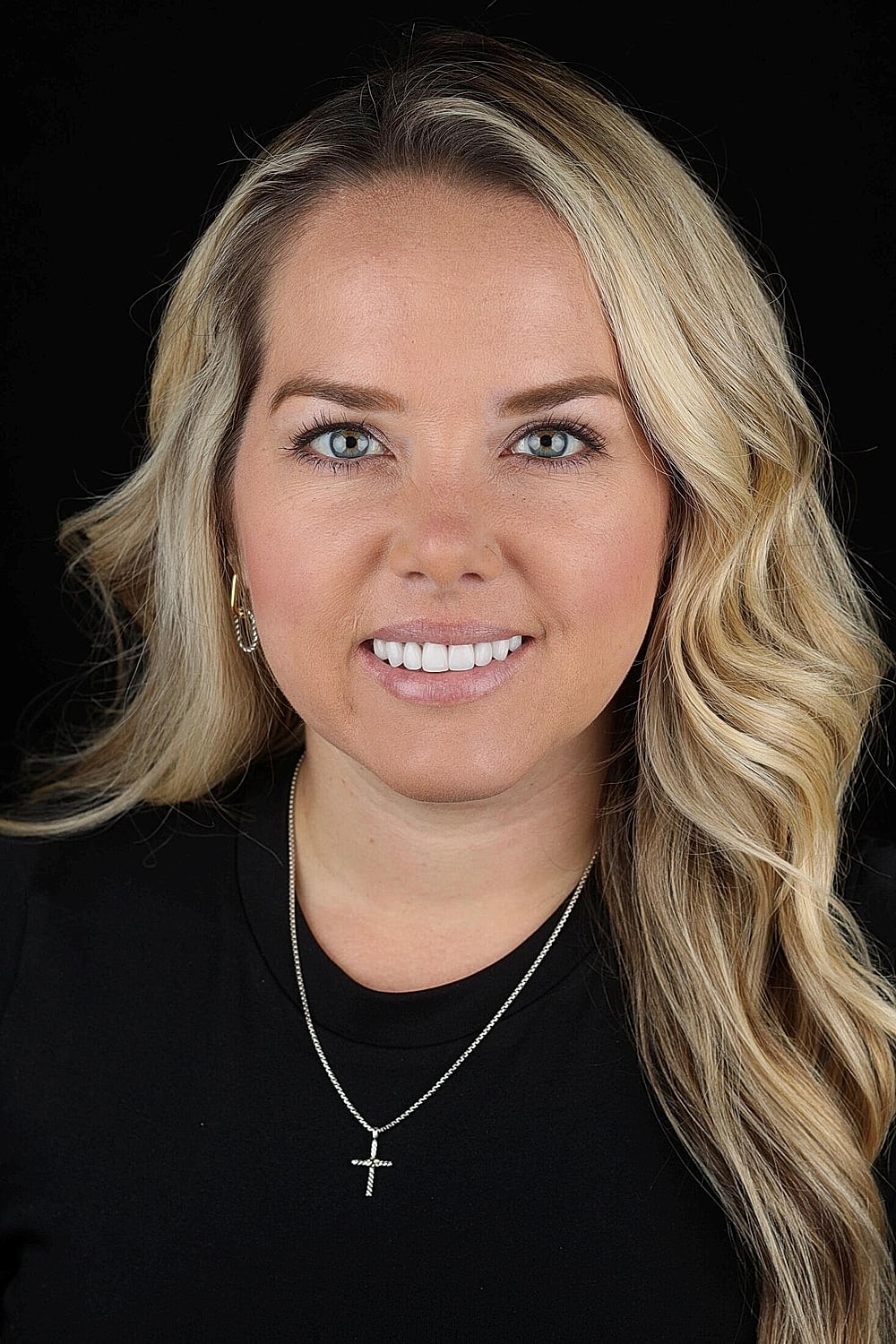 Smiling woman with blonde hair and necklace.