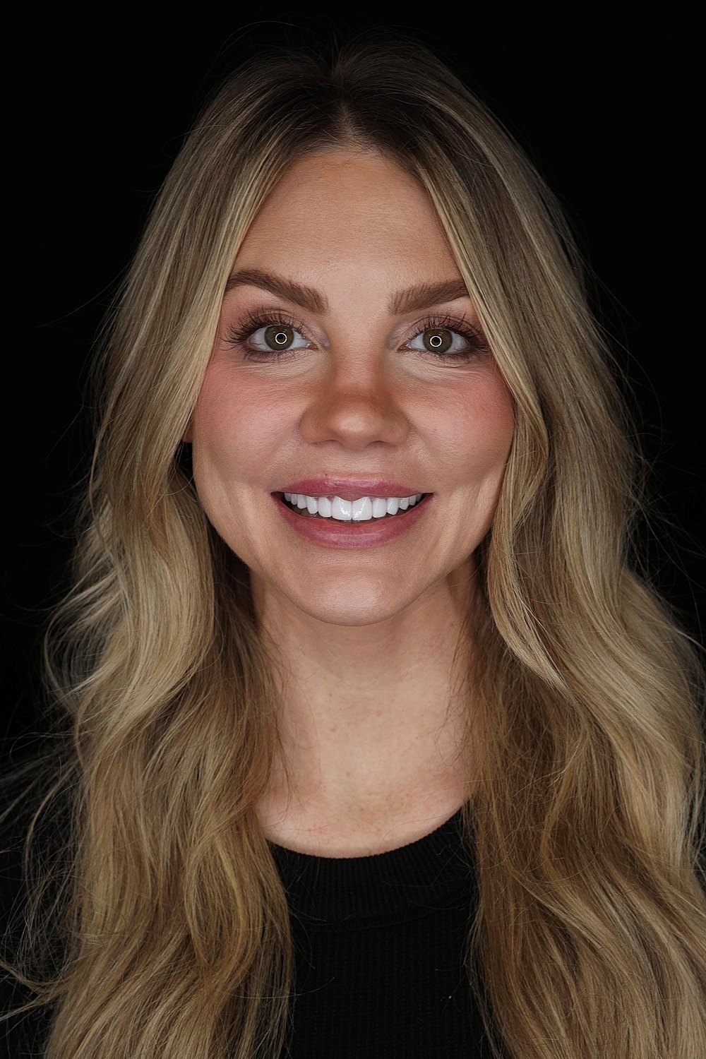 Smiling woman with long, wavy blonde hair.