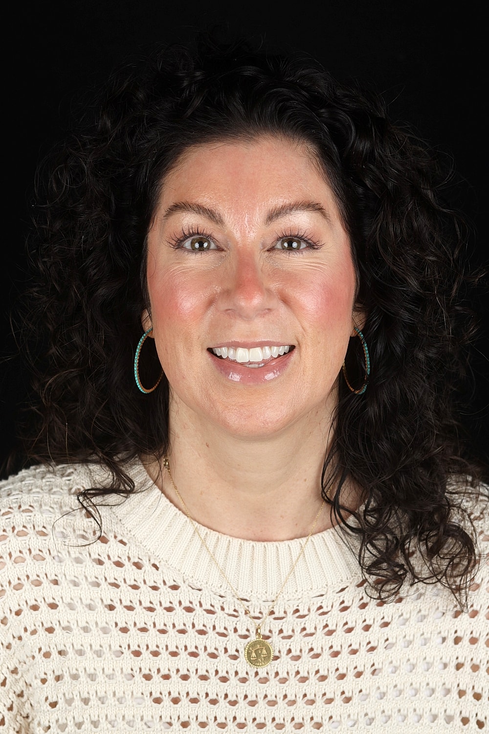 Smiling woman with curly hair and white sweater.
