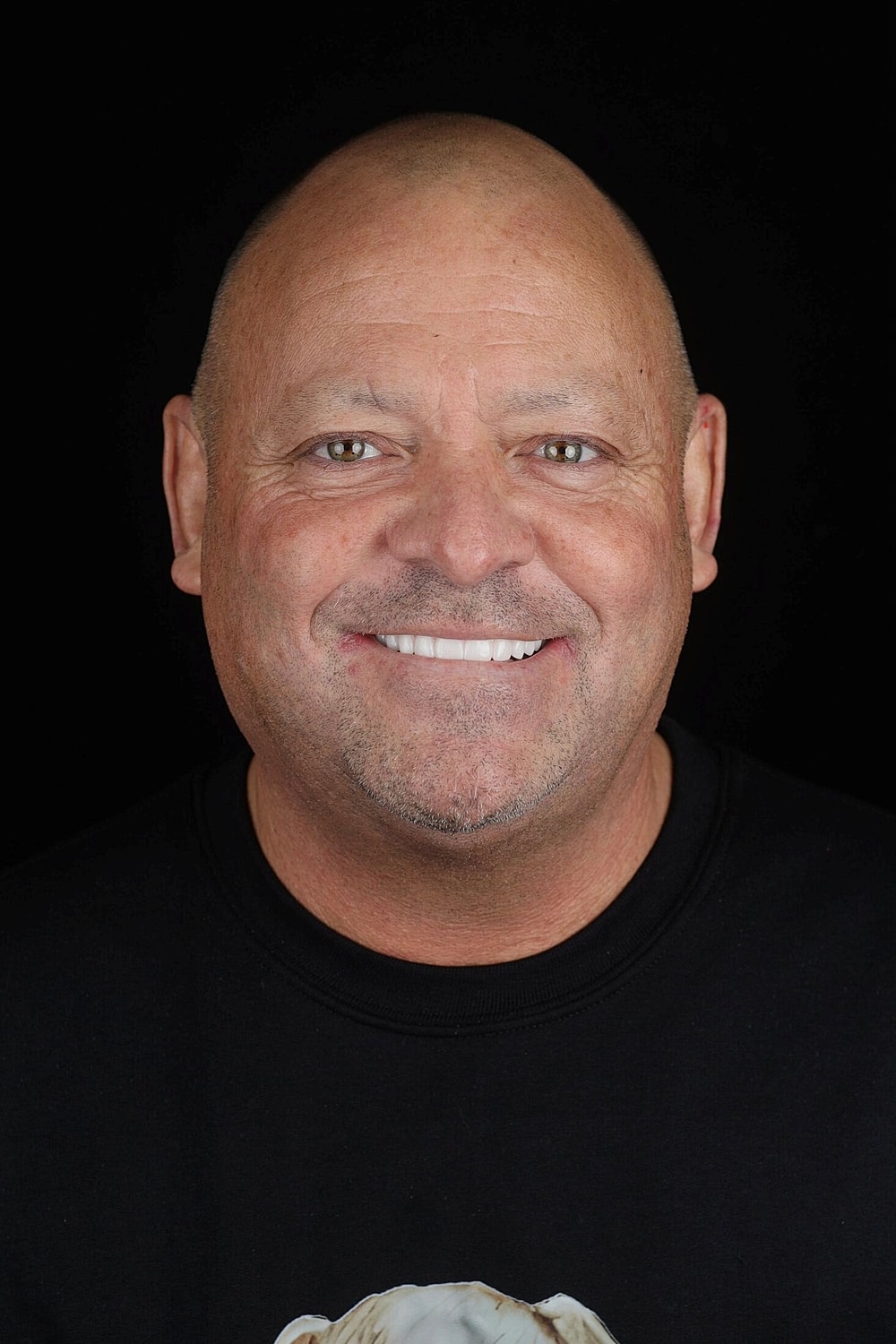 Smiling bald man in a black shirt.