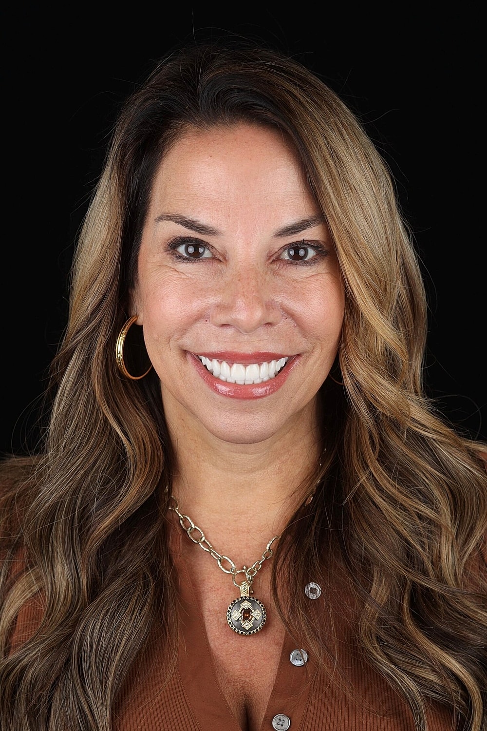 Smiling woman with long, wavy hair and necklace.