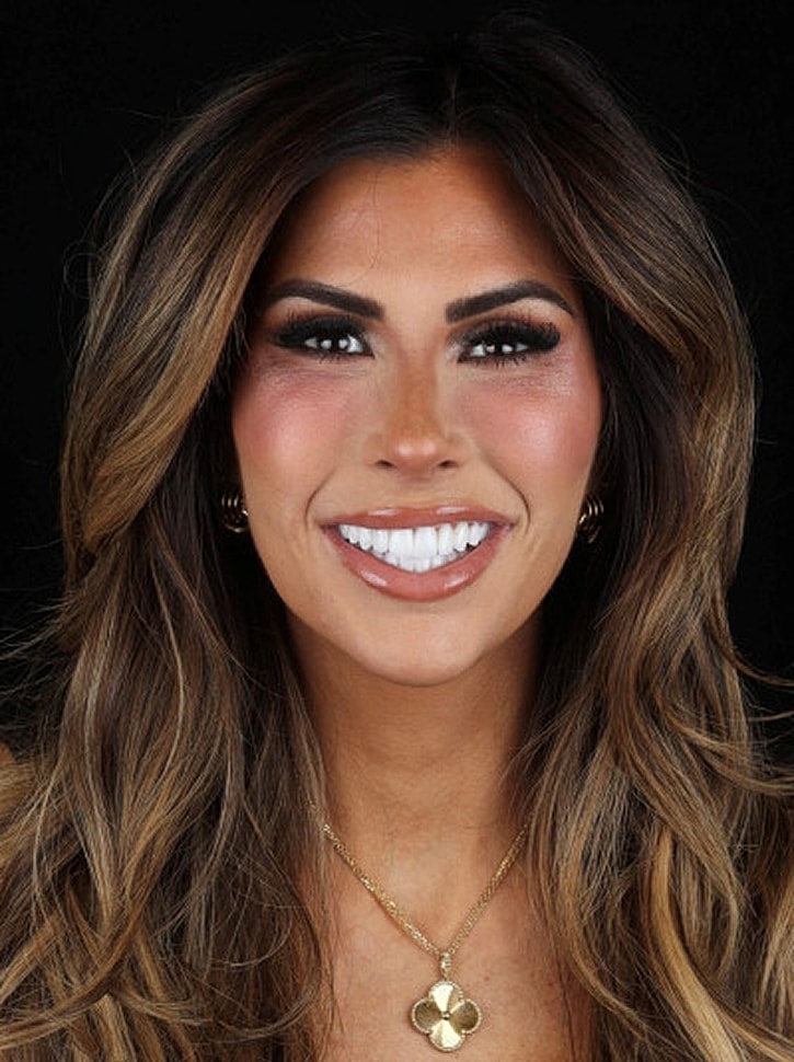 Smiling woman with long, wavy hair and necklace.