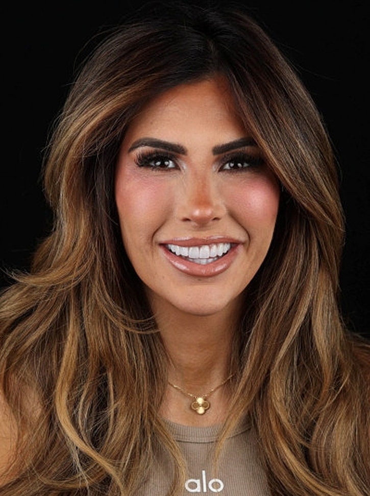 Smiling woman with long, wavy hair and makeup.