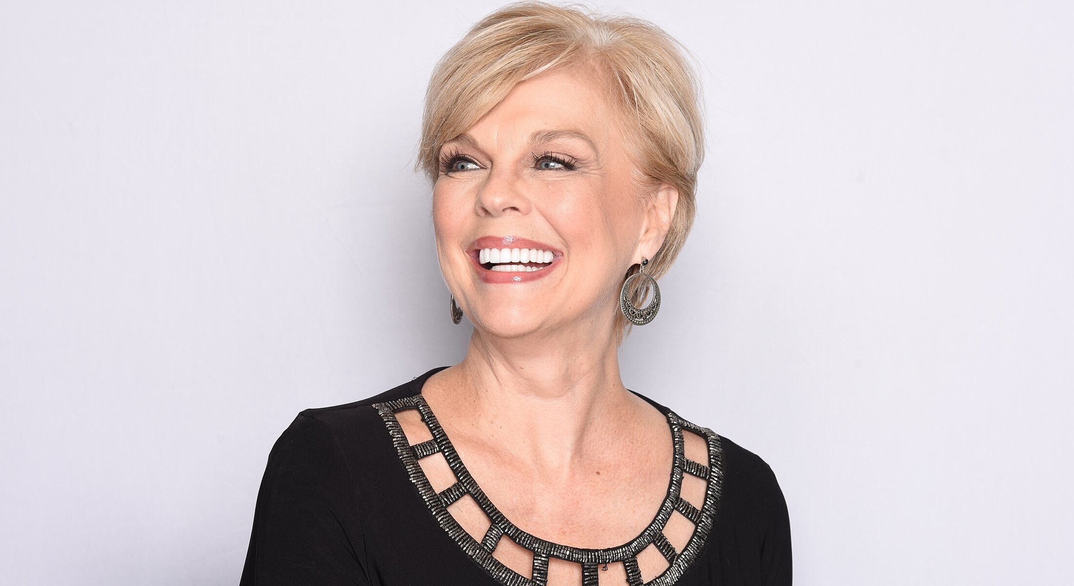 Smiling woman with short hair and earrings.