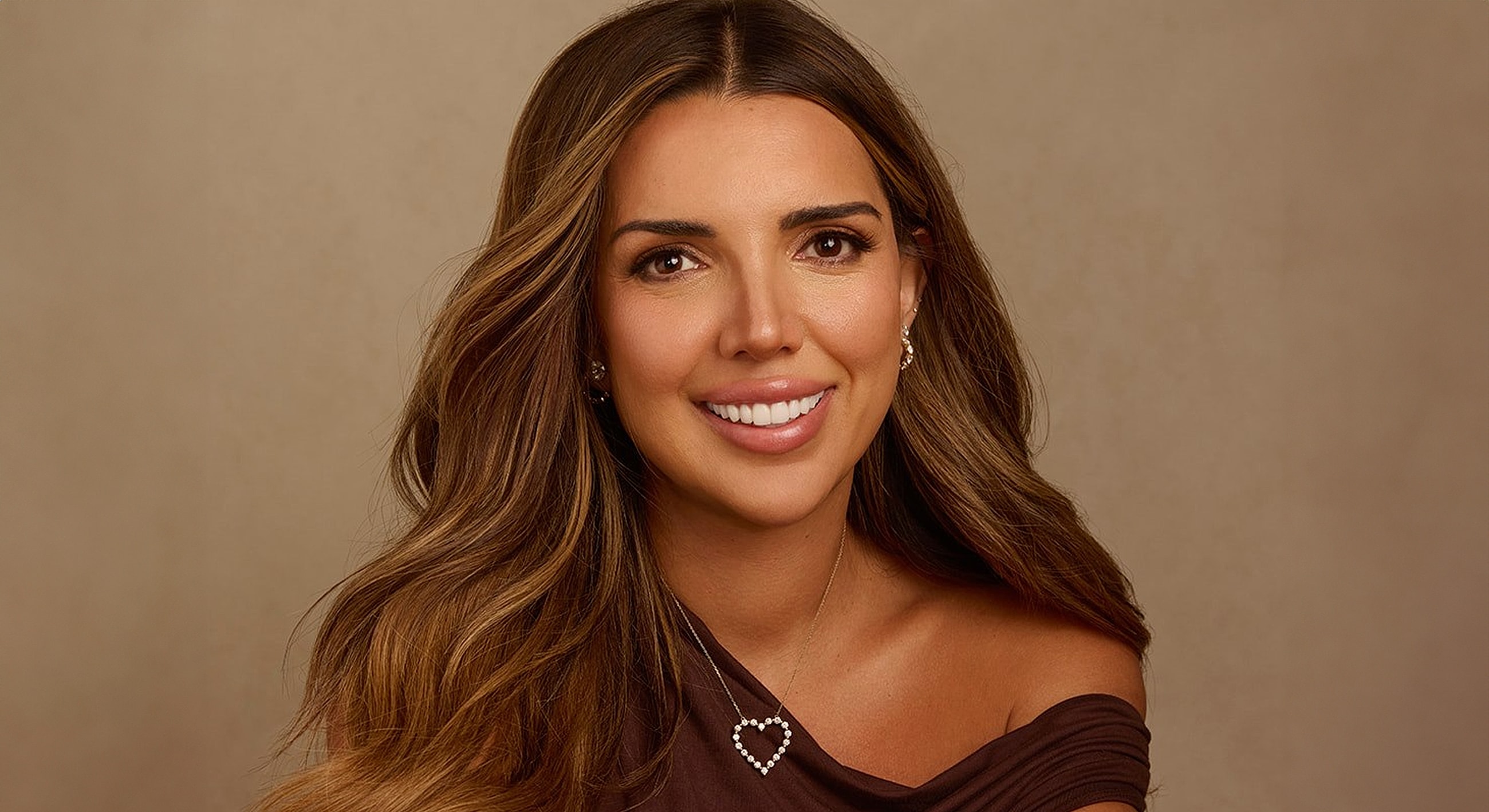 Smiling woman with long hair and heart necklace.