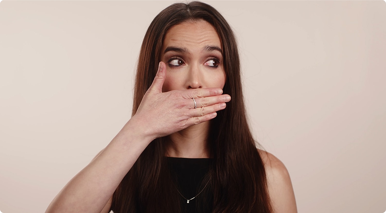 Woman covering her mouth with hand, surprised expression.